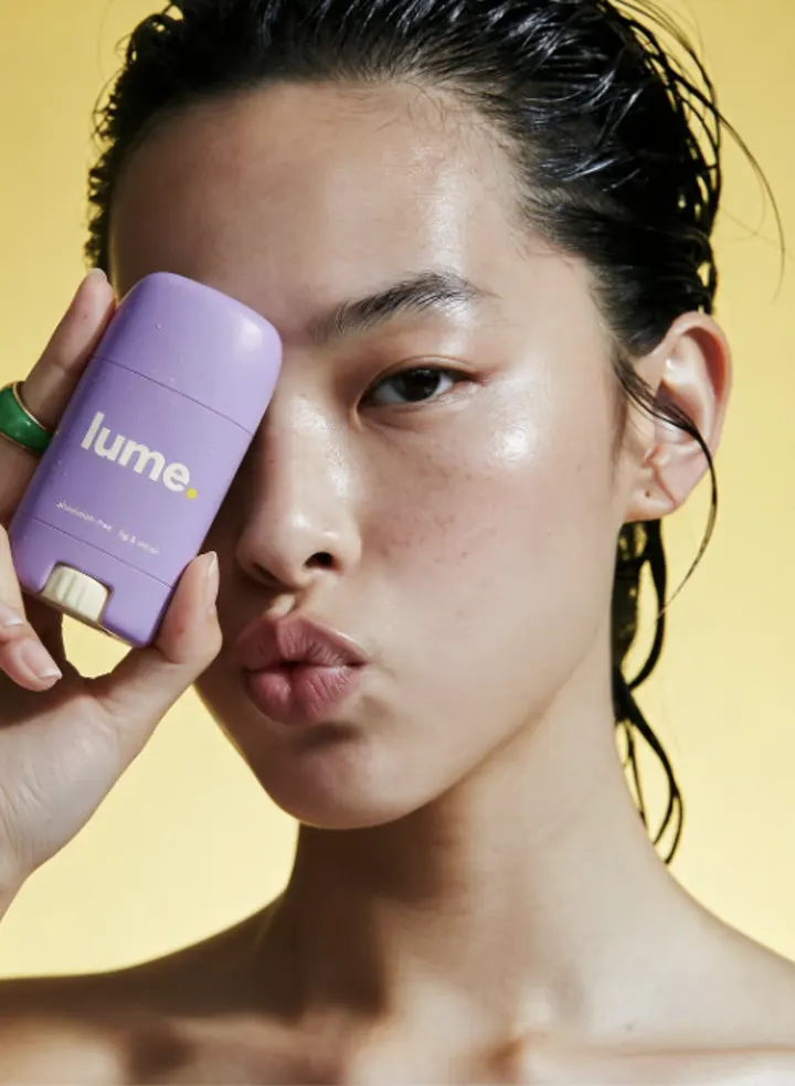 Beauty portrait with a lilac Lume product against a yellow background